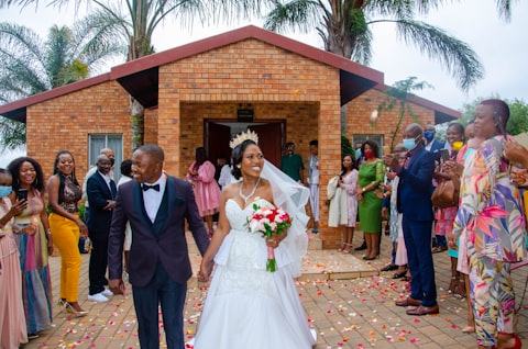 Wedding party walking out of a brick chapel past cheering guests
