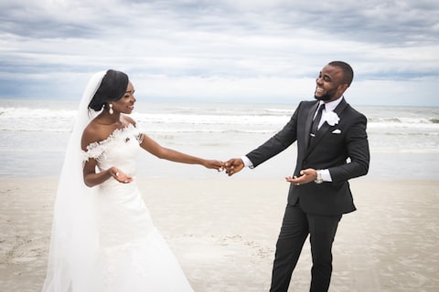 Bride and groom holding hands on the beach at their wedding