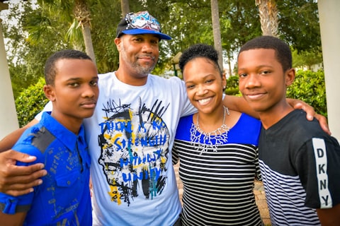 Family of four in matching blue accents smiling together under palm trees