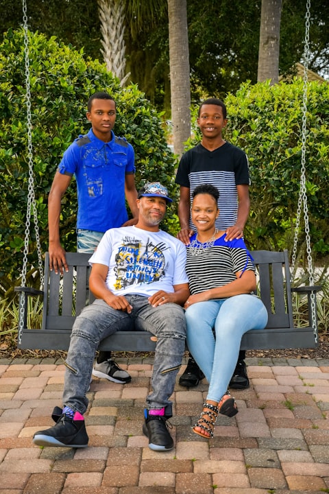 Family of four piled onto a porch swing surrounded by palms