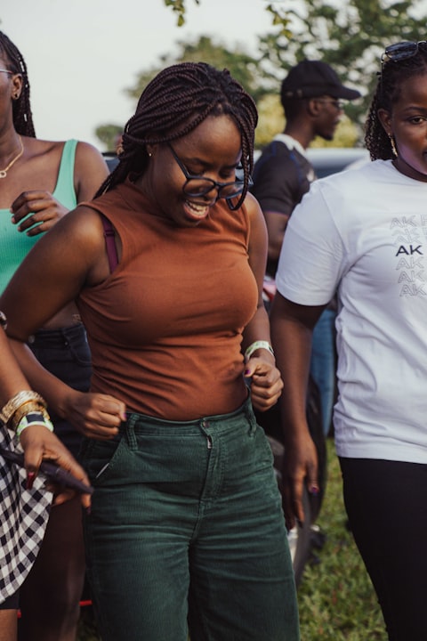 Friends cracking up mid-dance at an outdoor gathering, golden hour light