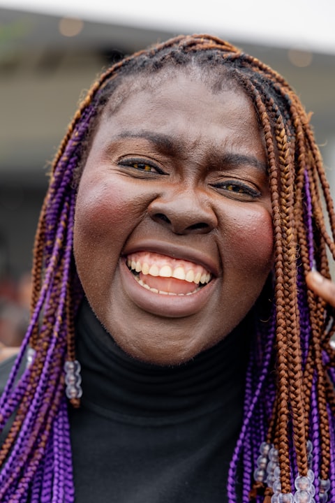 Close-up of a woman with purple-streaked braids laughing with her whole face